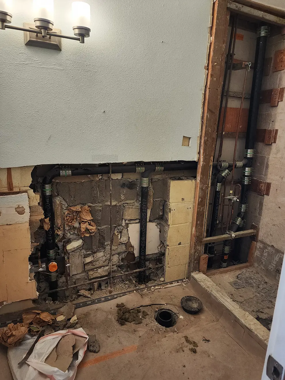 Bathroom wall opened exposing plumbing and drain